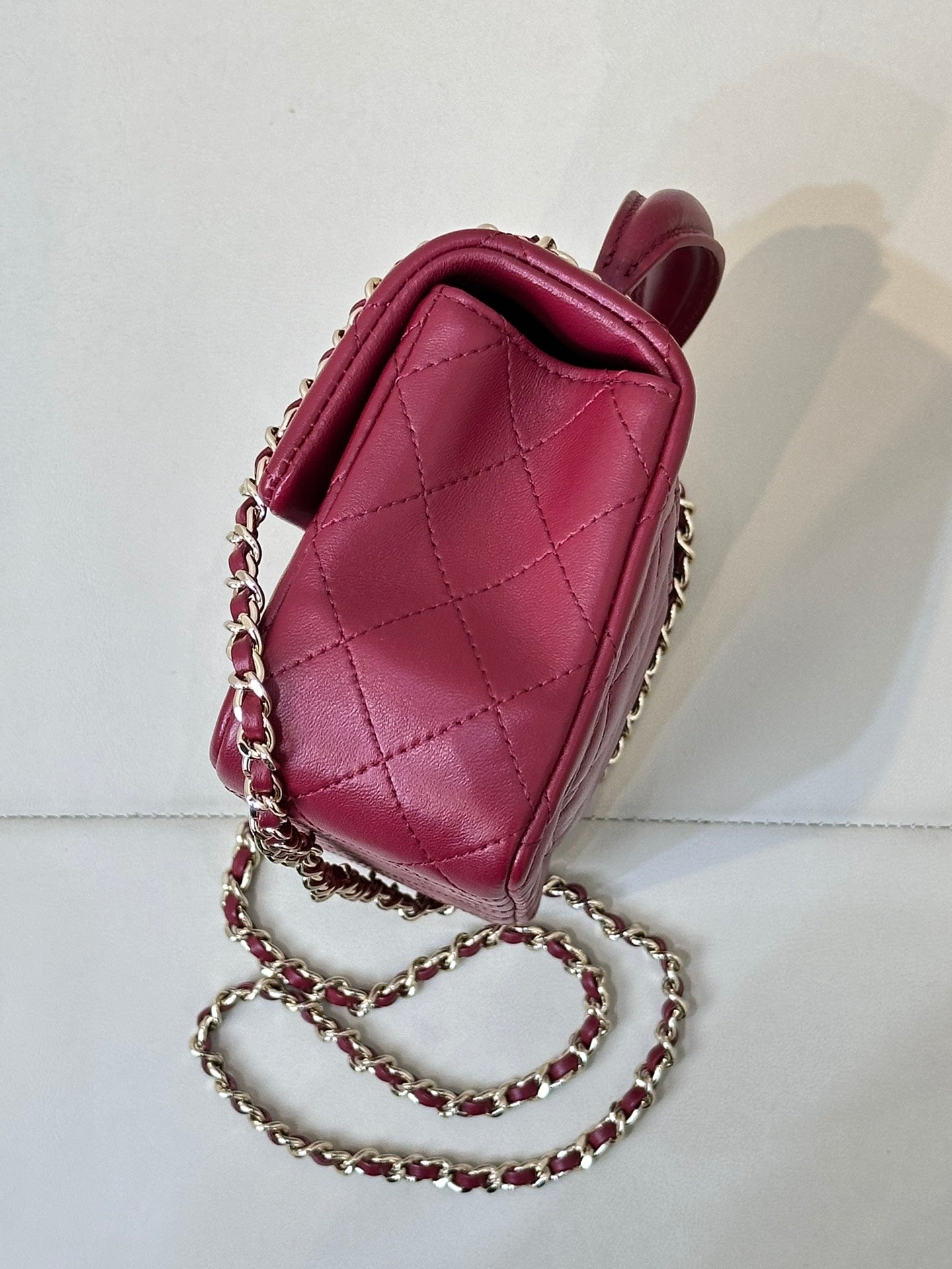 Chanel quilted flap bag side view, maroon-pink leather with chain shoulder strap