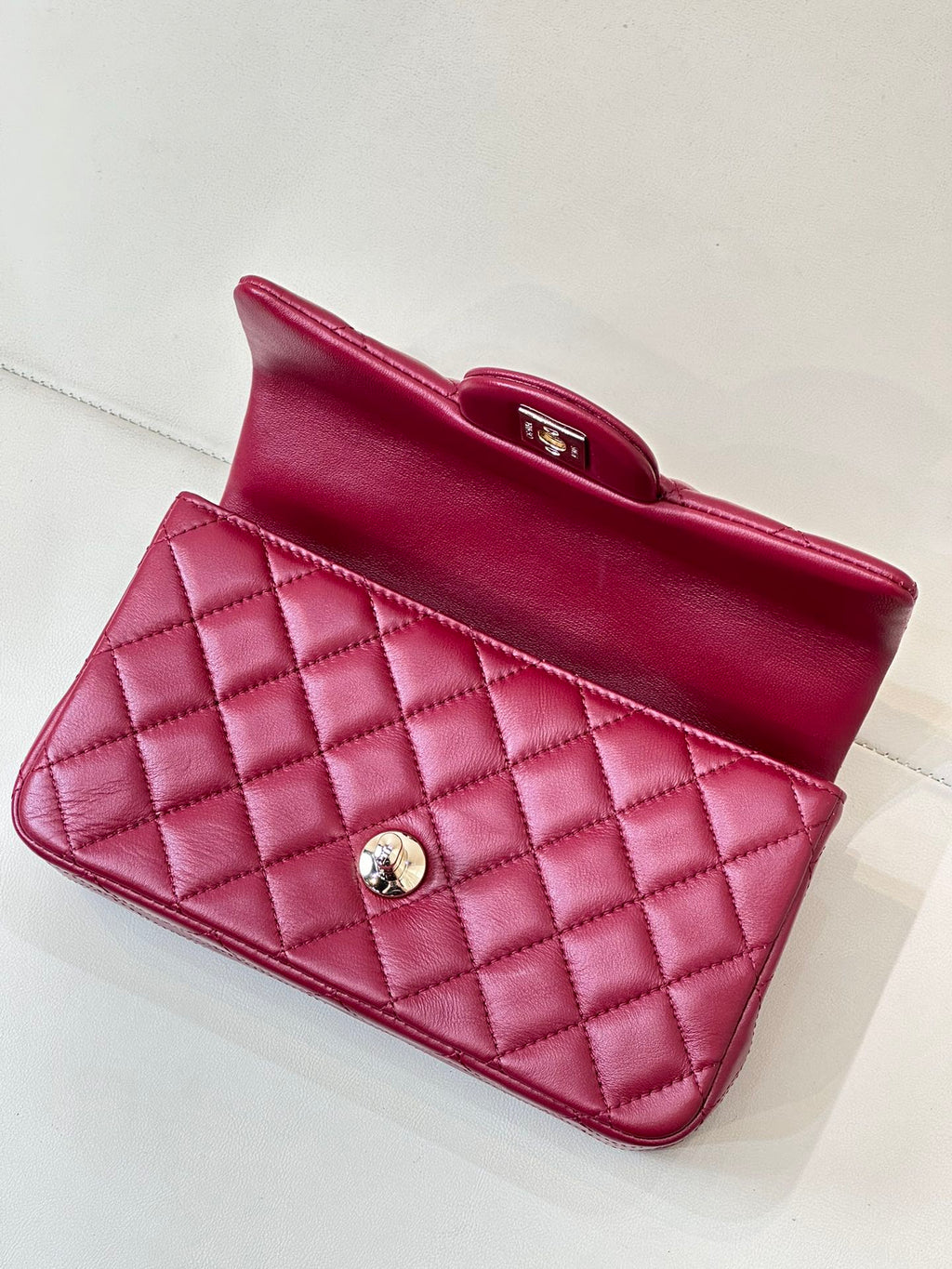 Chanel quilted flap bag open-top view, maroon-pink leather with gold clasp