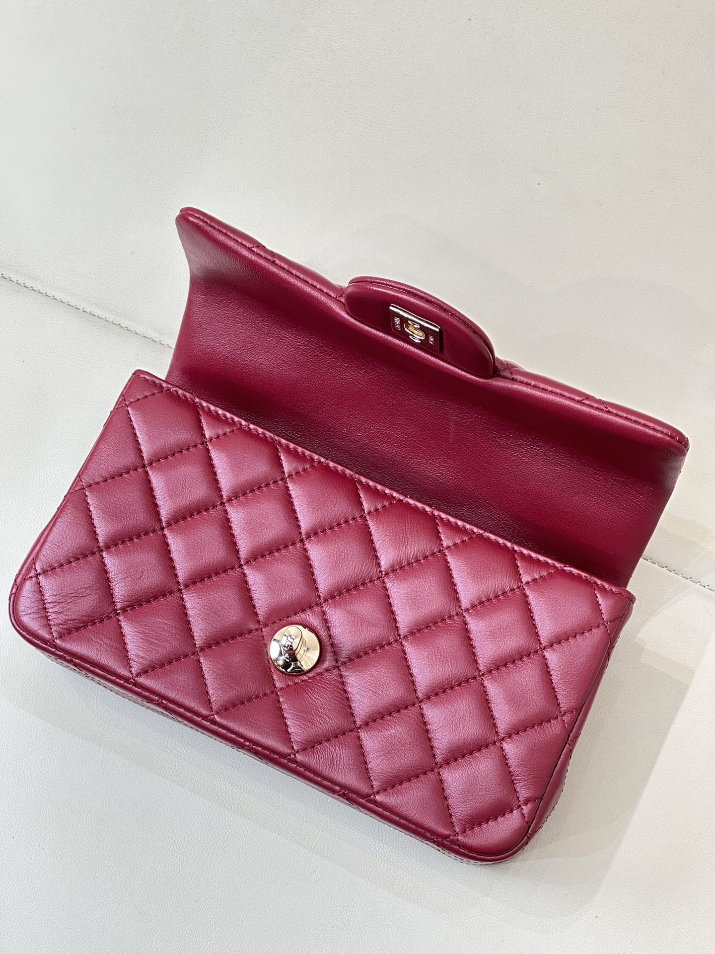 Chanel quilted flap bag open-top view, maroon-pink leather with gold clasp