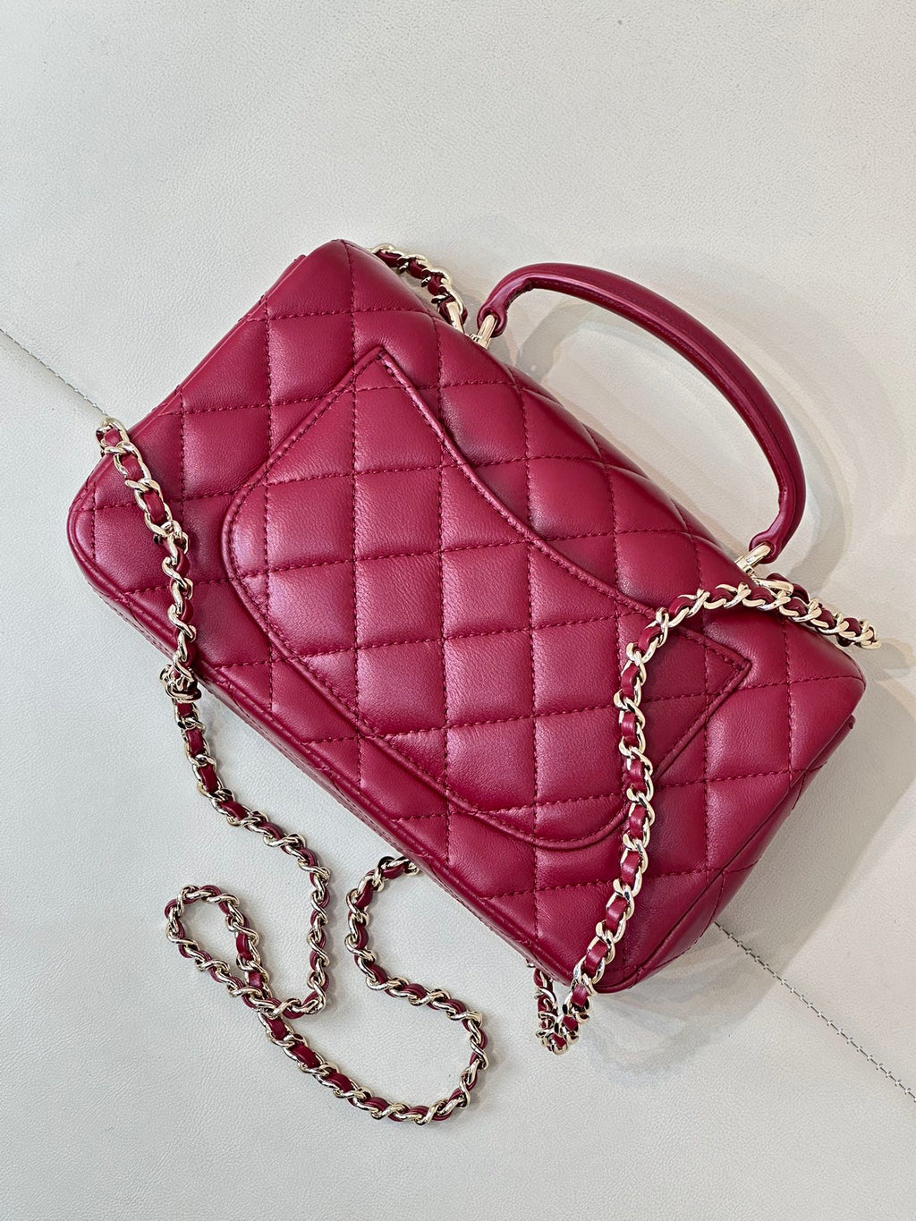 Chanel quilted flap bag angled view, maroon-pink leather with chain strap
