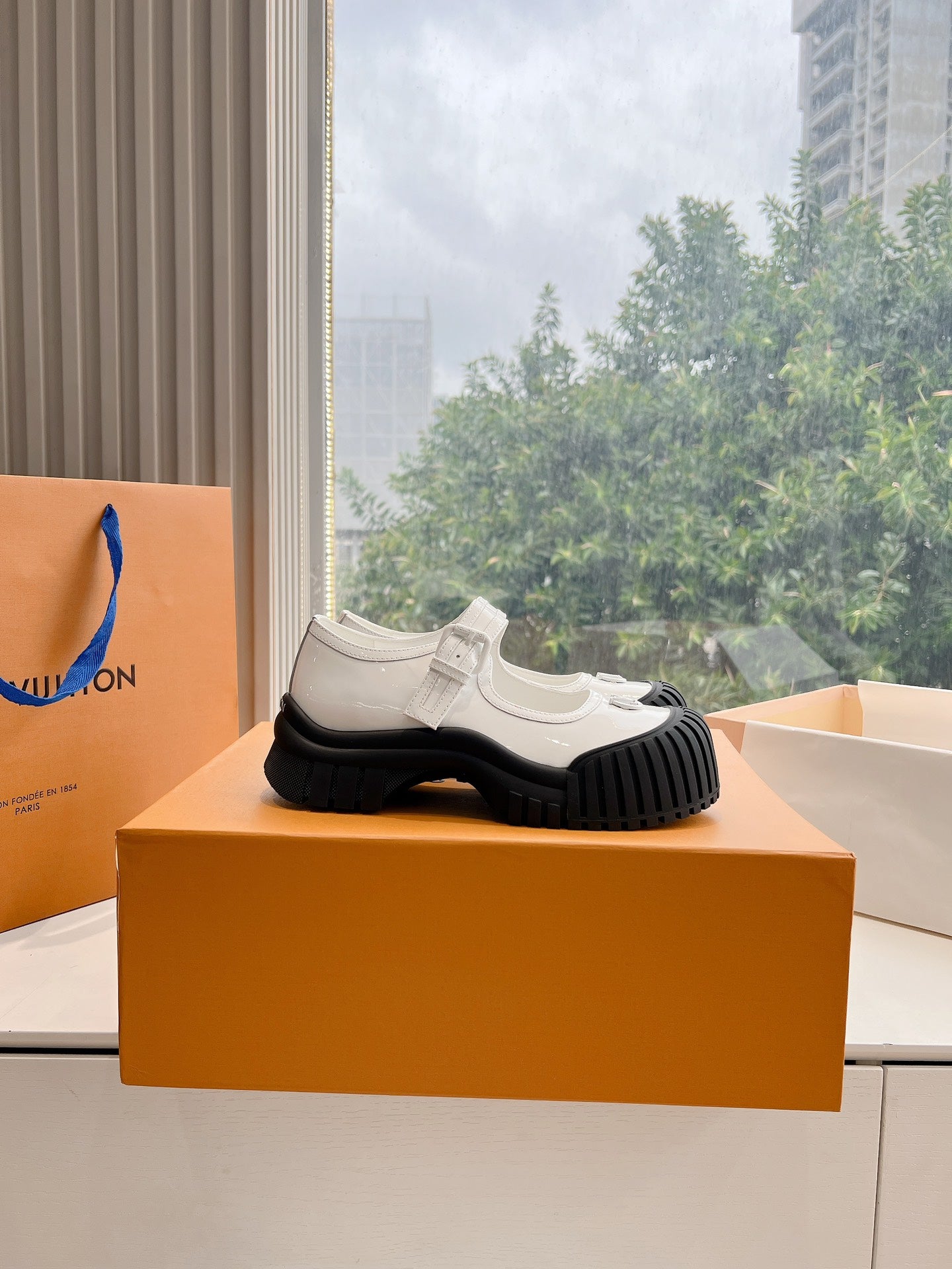White and black Louis Vuitton unisex sneakers, sole-up view on shoebox