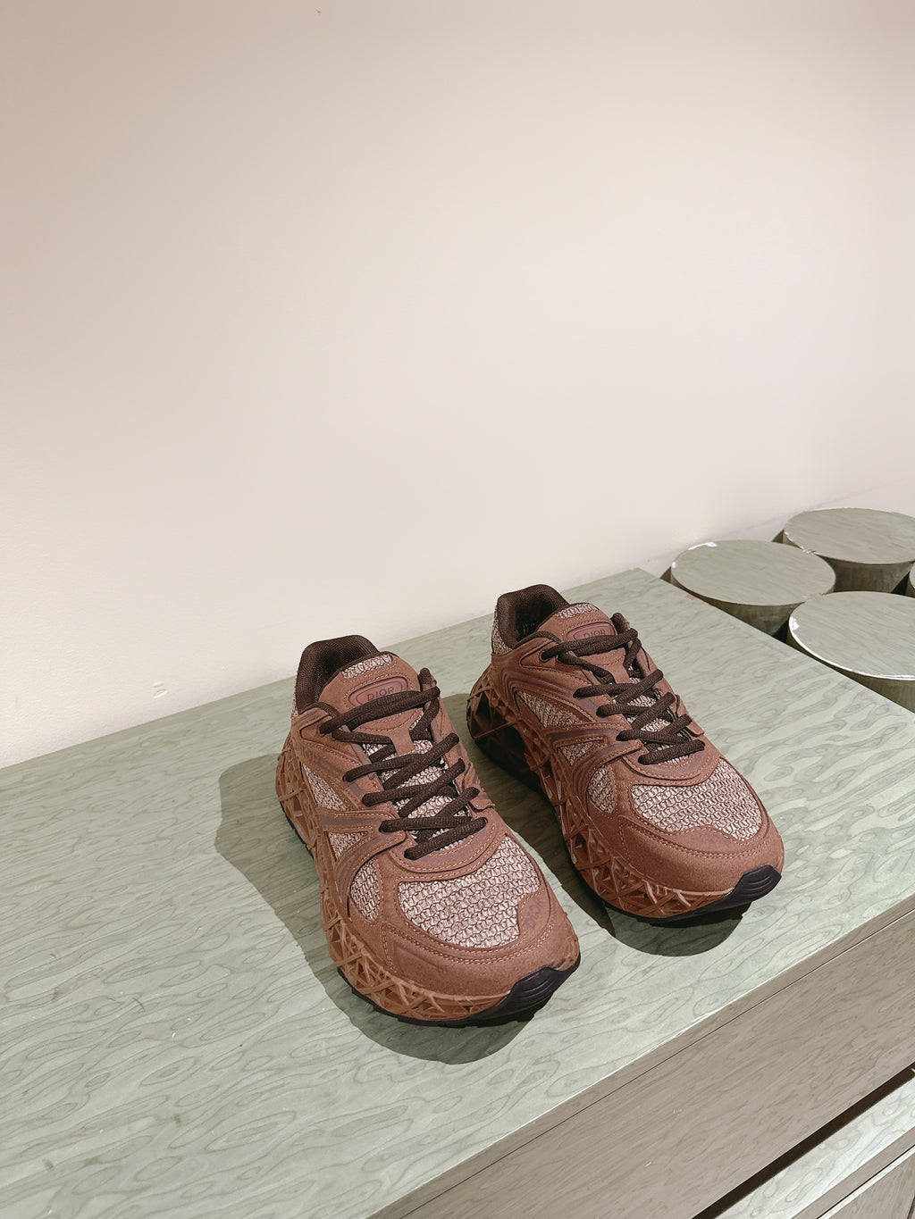 Unisex sneakers on display surface, tan uppers with brown tread soles