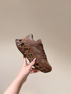 Unisex sneaker held in hand, tan mesh upper and brown lattice-pattern sole