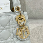 Dior bag close-up: gold clasp on white quilted leather with charm detail