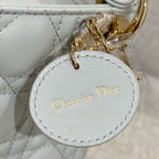 Dior bag close-up: round "Christian Dior" tag charm on white quilted leather