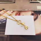 Gold charm necklace with clover-like link, star, and pearl dangle