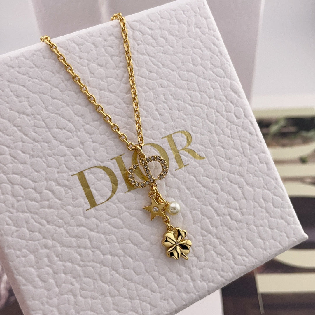 Gold charm necklace with star, flower, and pearl drop