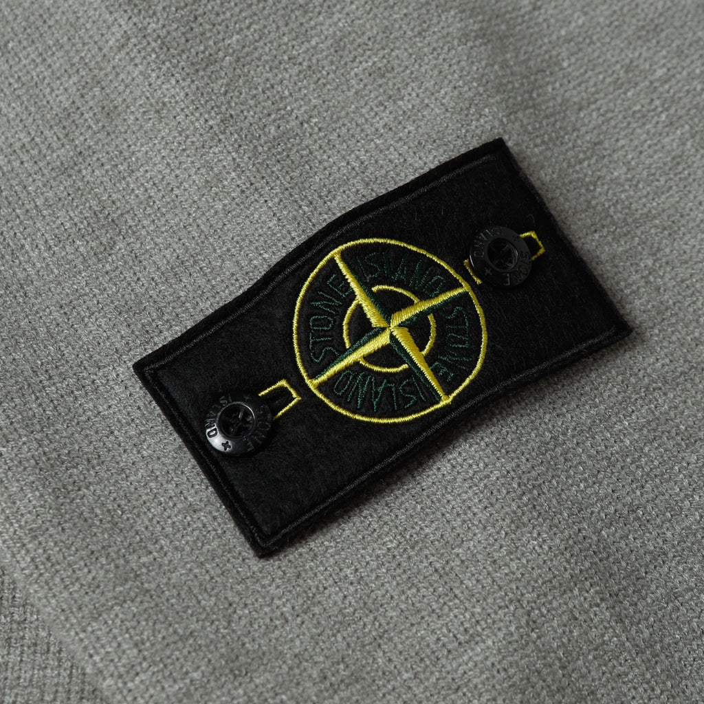 Stone Island black logo patch with yellow emblem on gray knit sweater sleeve