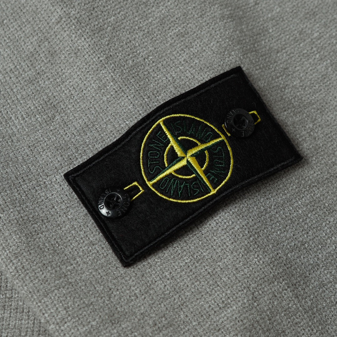 Stone Island black logo patch with yellow emblem on gray knit sweater sleeve