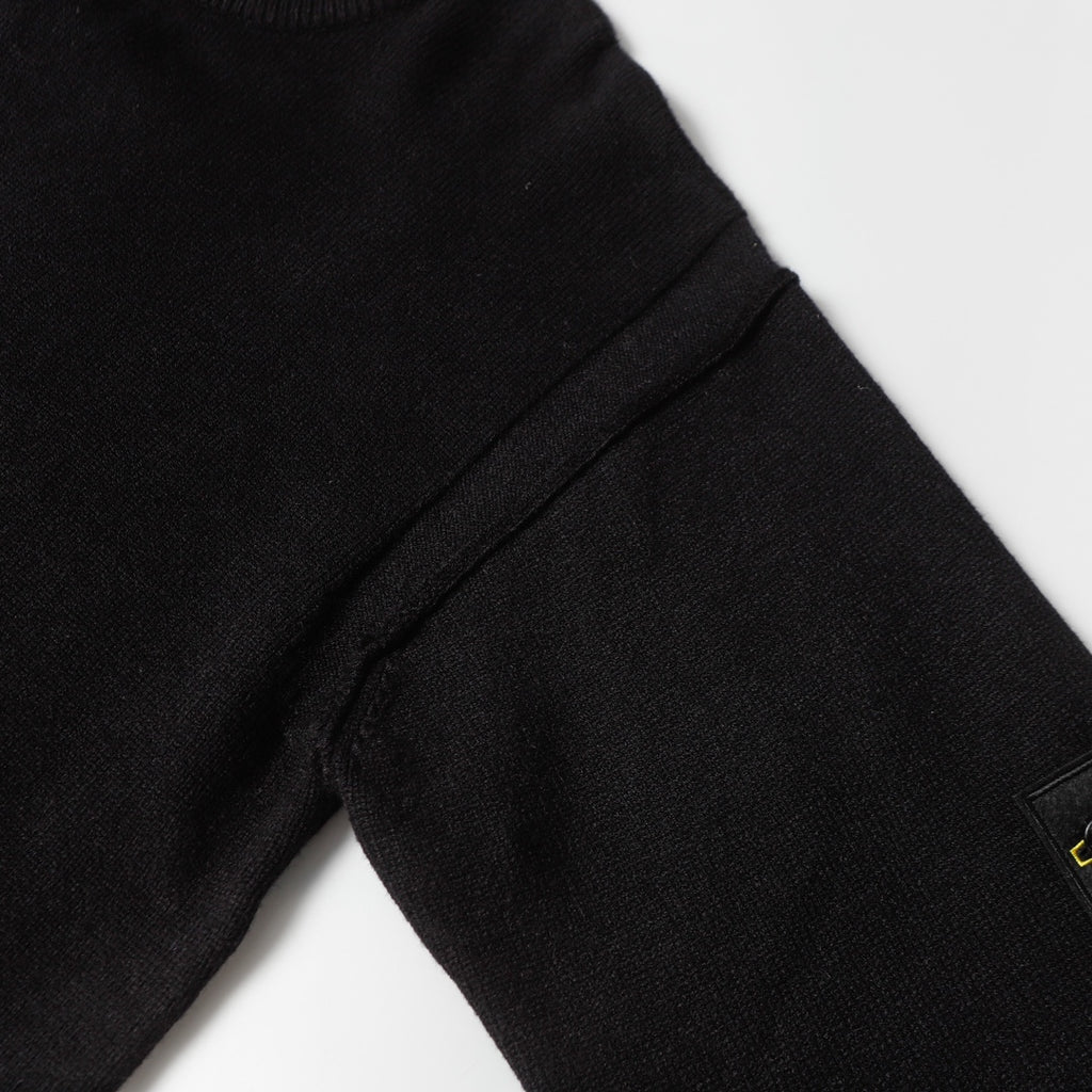 Black knit sweater sleeve seam with ribbed cuff and stitched panel