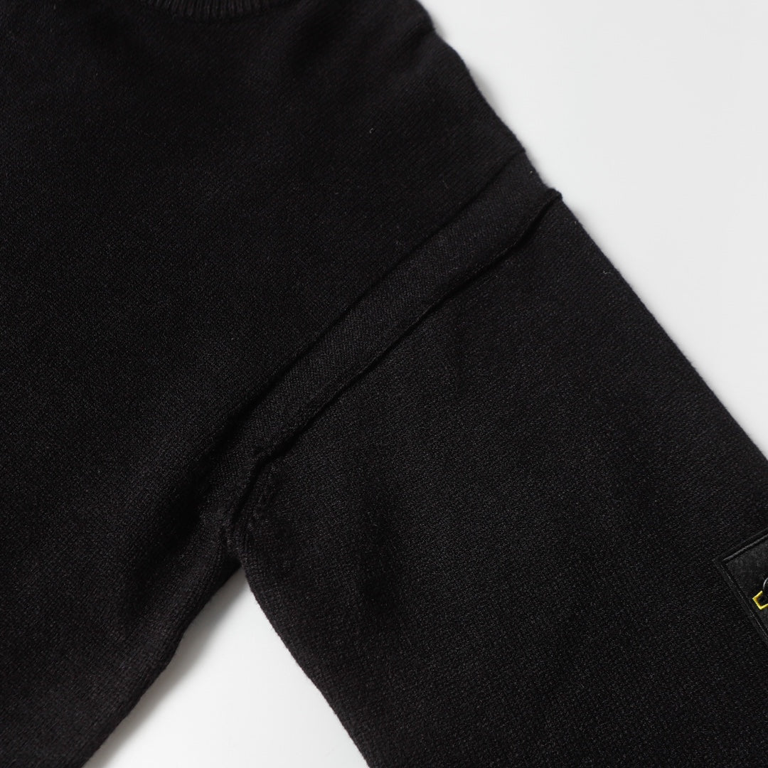 Black knit sweater sleeve seam with ribbed cuff and stitched panel