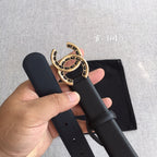 Black belt with gold CC medallion buckle, held with strap holes visible