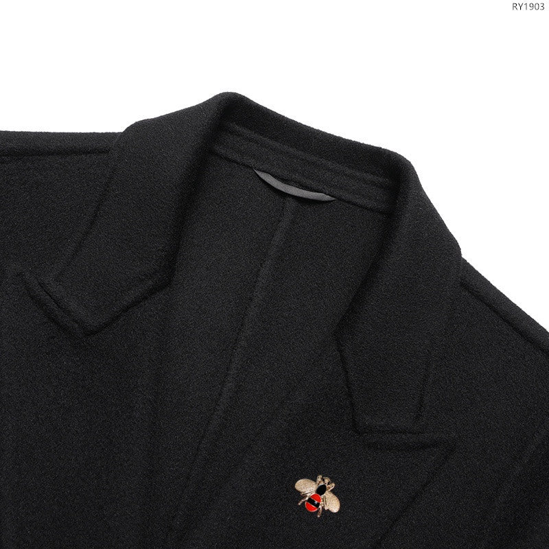 Black overcoat lapel with small embroidered logo pin