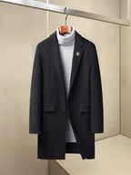 Dark long wool coat with notch lapels, patch pockets, and small chest pin