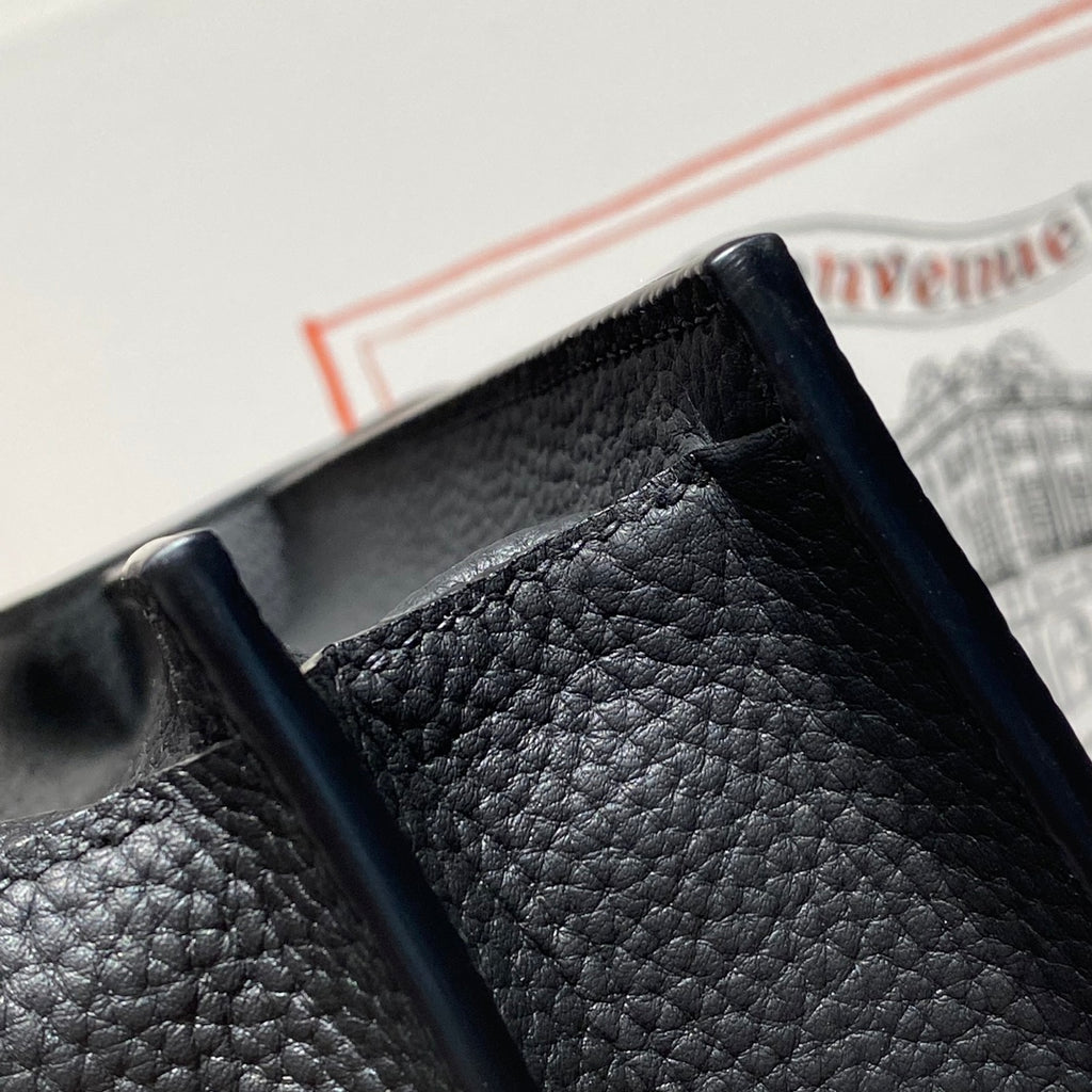 Hermes bag top edge close-up with textured leather and strap attachment hardware.