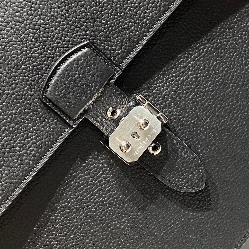 Hermes bag clasp close-up with silver-toned lock plate and round hardware studs.