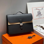 Hermes bag in dark leather with top handle, front flap, and metal lock clasp.