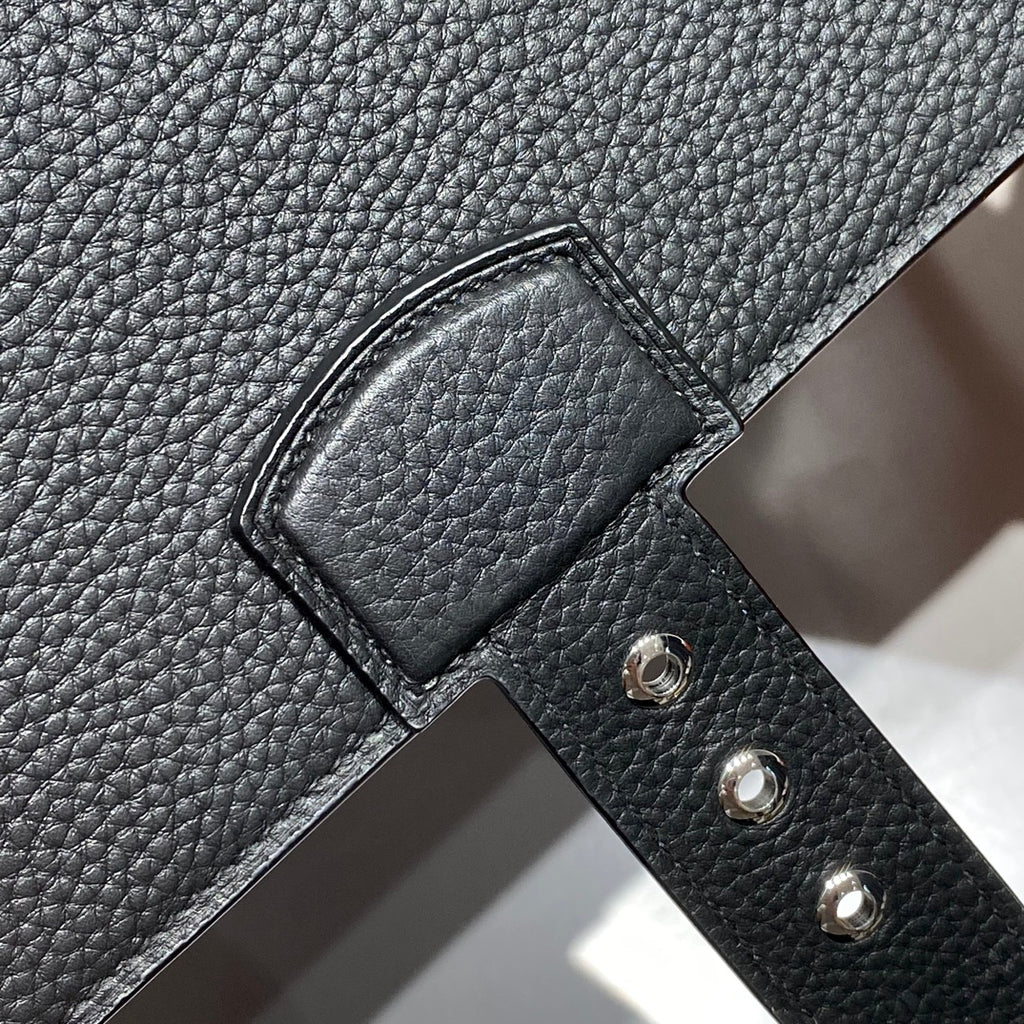 Hermes bag front leather close-up with strap slot and three metal rivets.