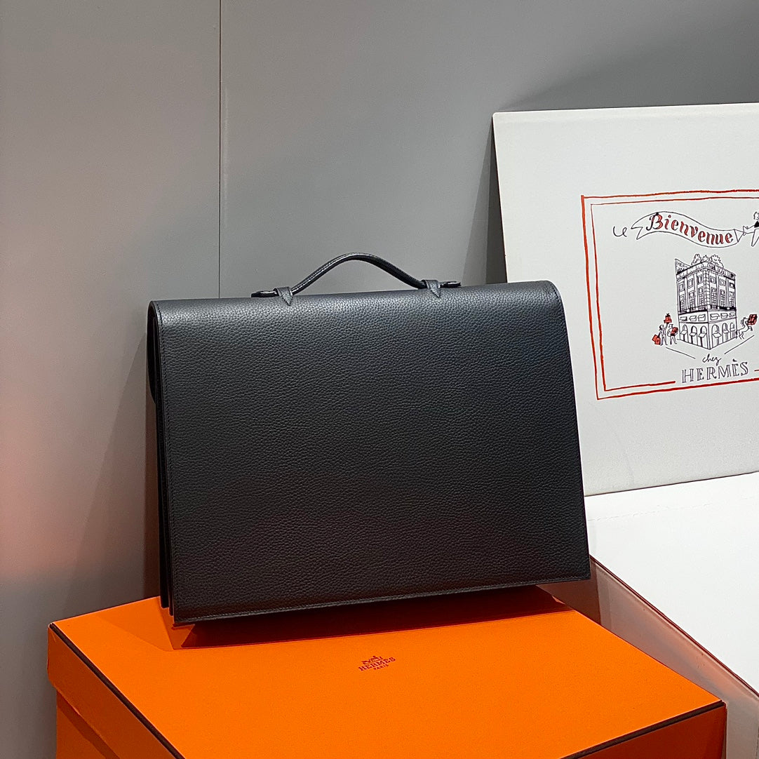 Hermes bag in dark leather with structured front and top handle, side angle view.