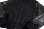Black snap-front varsity jacket with zip pockets and leather-look sleeves