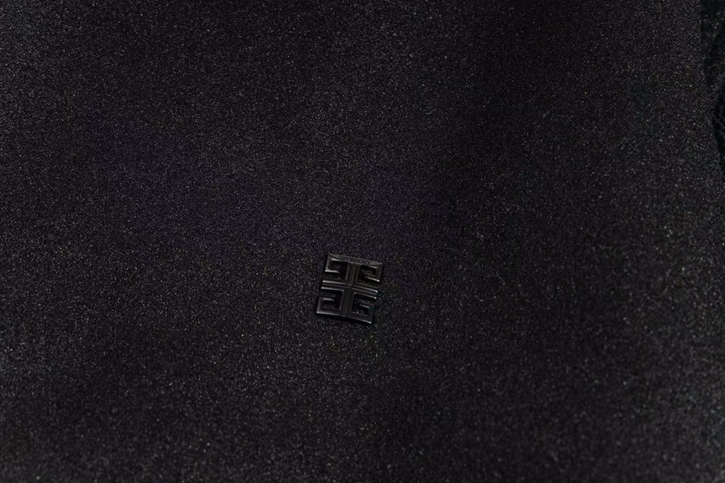 Small metallic logo emblem on black varsity jacket chest
