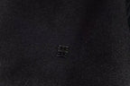 Small metallic logo emblem on black varsity jacket chest