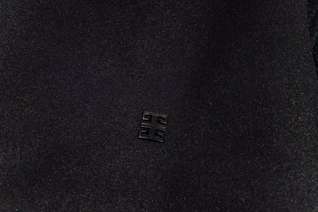 Small metallic logo emblem on black varsity jacket chest