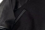 Black zipper pocket detail on varsity jacket body with textured leather sleeve