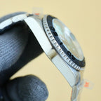 Rolex stainless steel wristwatch side view with black bezel and textured minute markers.