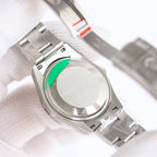 Steel watch caseback with green circular detail and screw-down crown