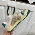 Gucci sneakers on a white door: cream leather, green side stripe, and sparkling front