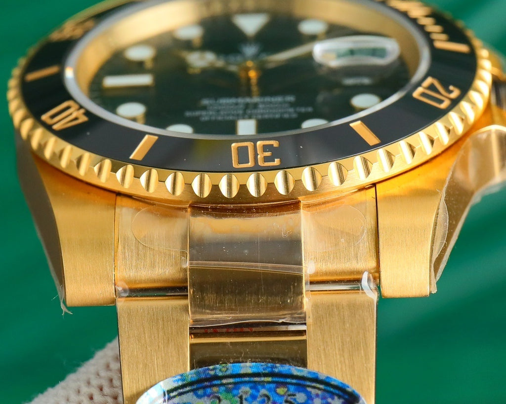 Gold-tone watch bezel with black insert, orange markers, and crown detail