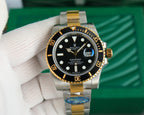 Rolex watch with black dial and gold bezel on two-tone metal bracelet