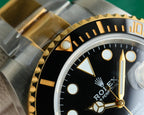 Rolex watch close-up of bezel and crown area, black dial with gold hour markers
