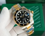 Rolex watch angled view, black dial with gold markers and date window, metal bracelet