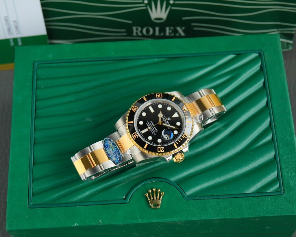 Rolex watch resting in presentation box, two-tone bracelet and black dial with gold accents