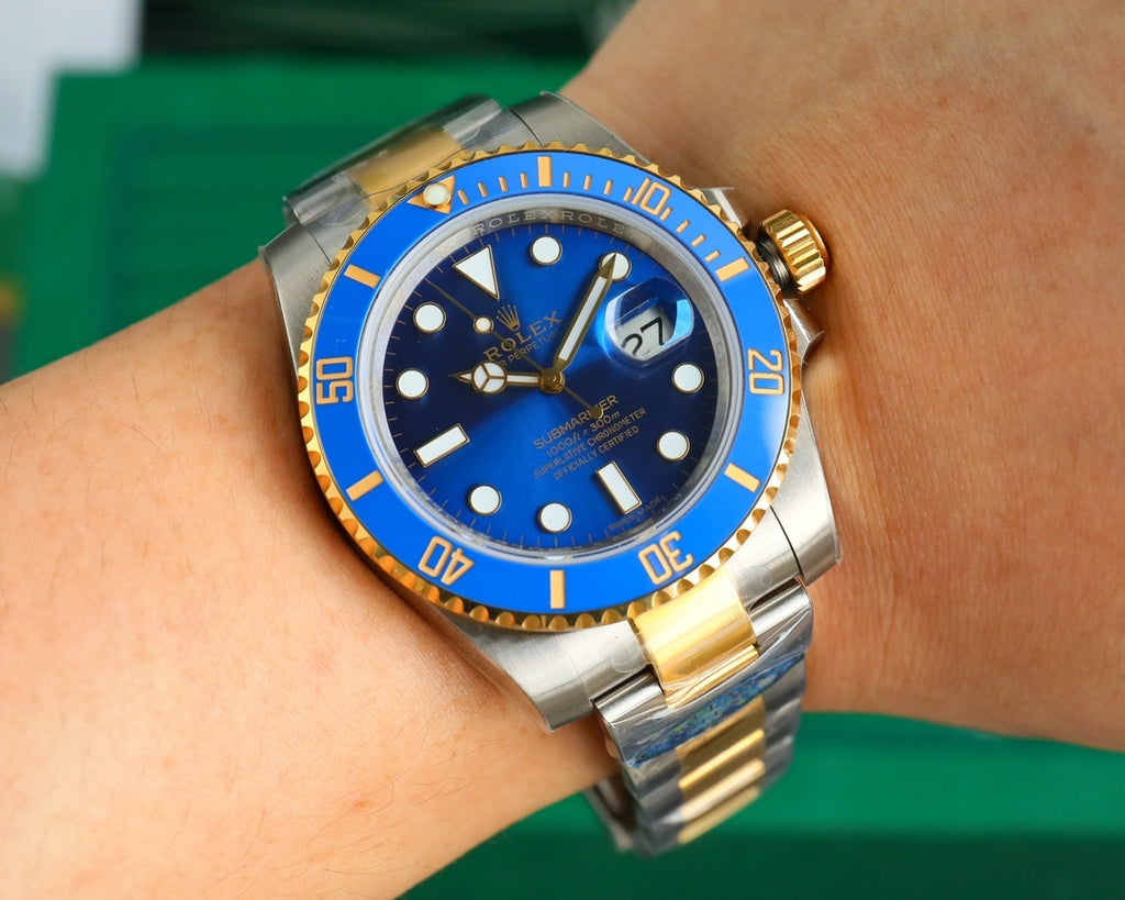 Rolex watch on wrist with blue dial, gold bezel, and steel-and-gold bracelet