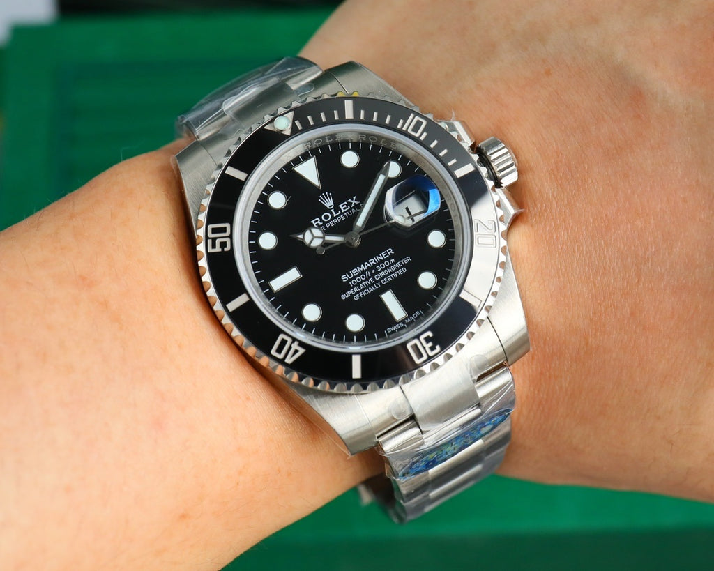 Rolex watch on wrist with black dial and stainless steel bracelet