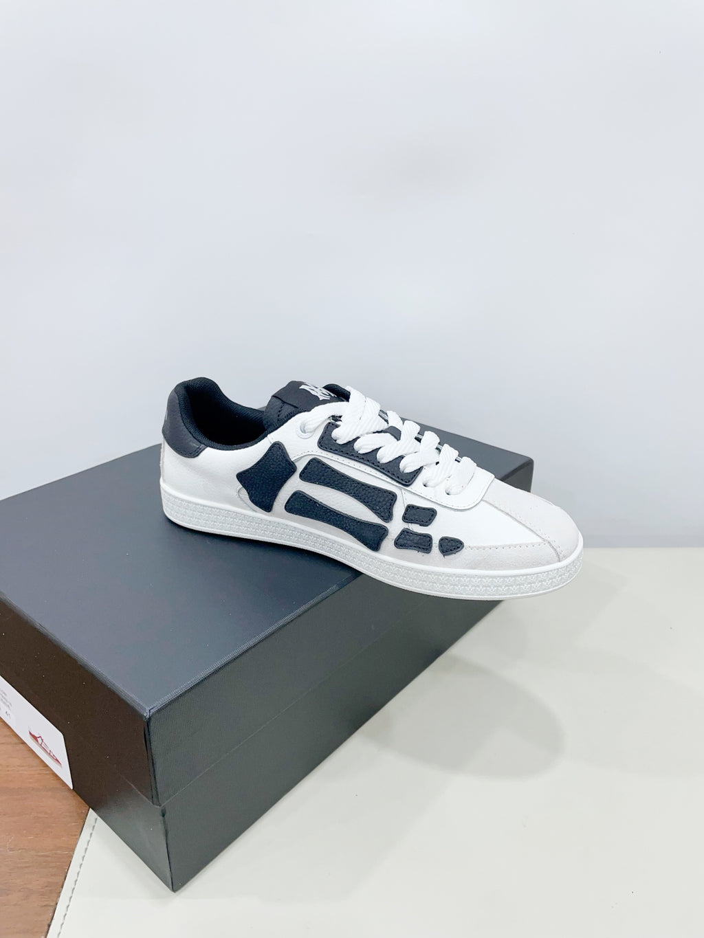 Pair of white low-top sneakers with navy patterned details on a box