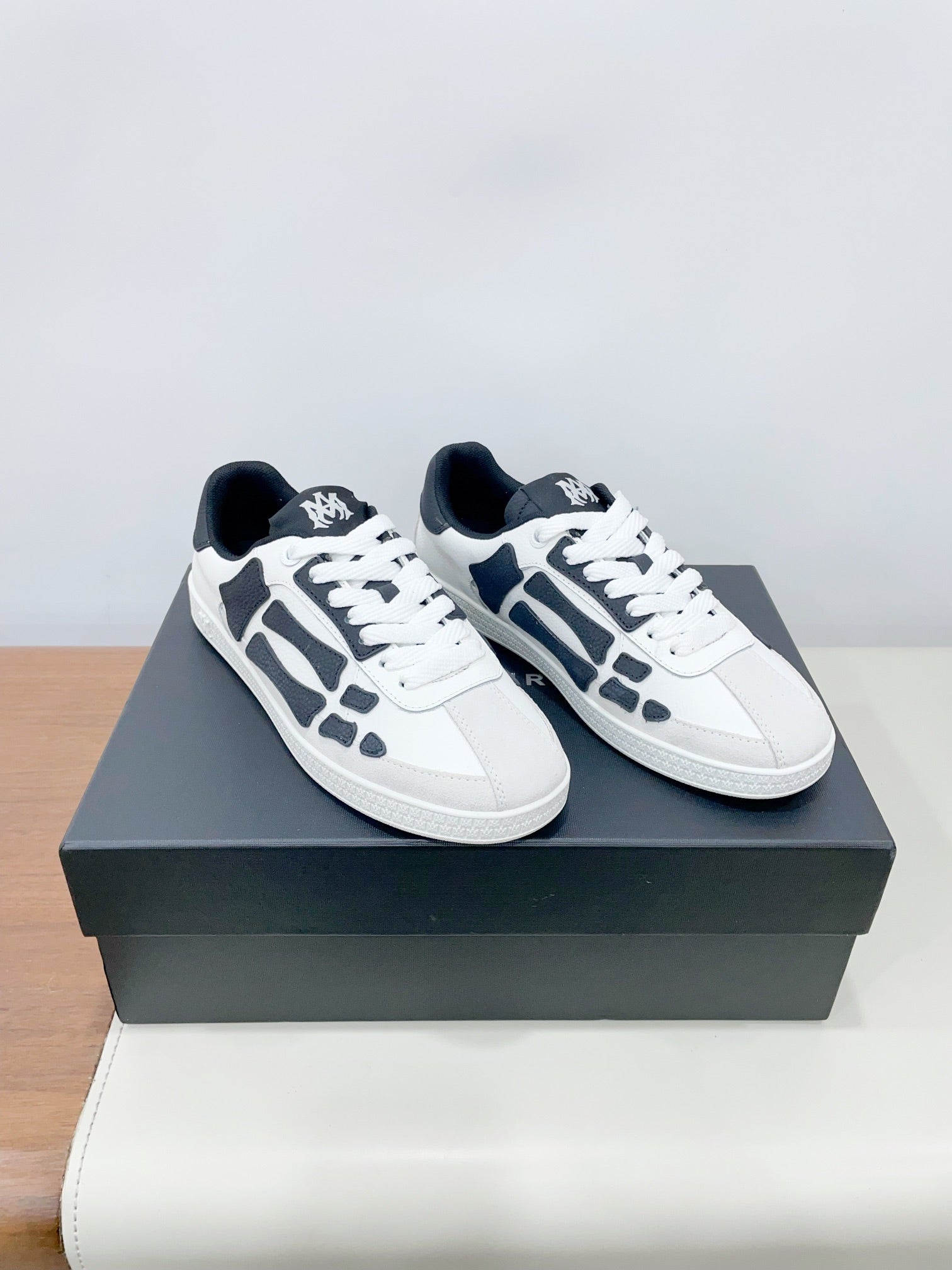 White low-top sneakers with navy graphic overlays and black rubber accents