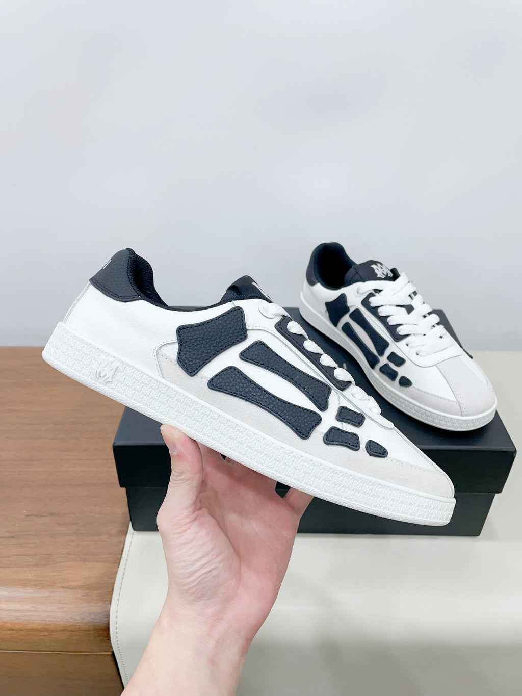 White and navy low-top sneakers, side view held in hand
