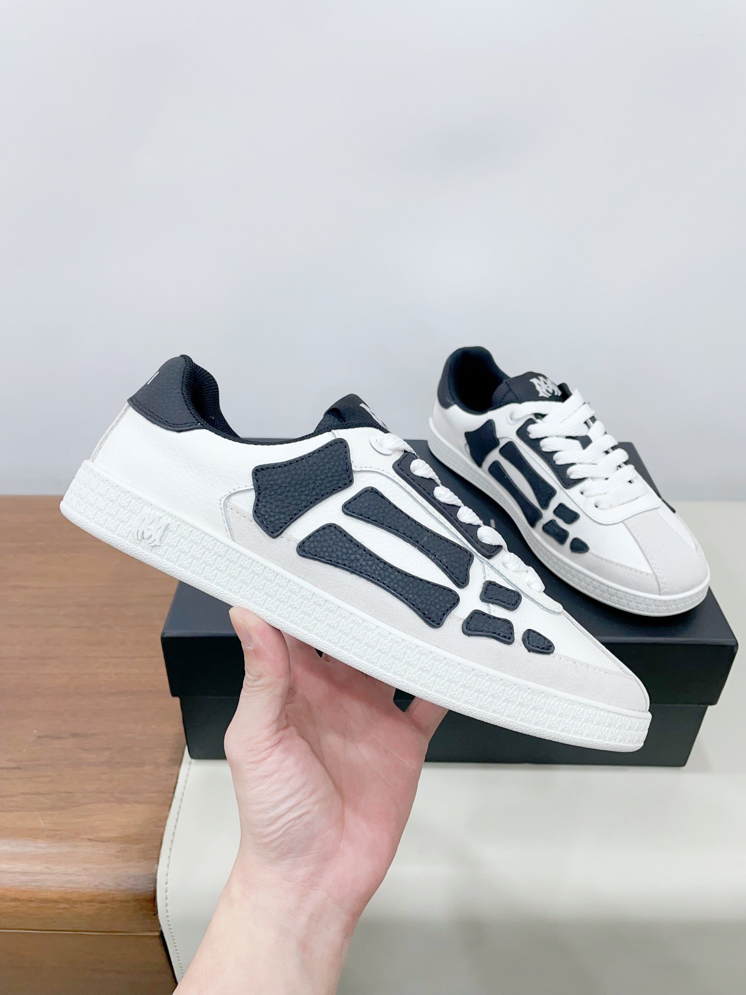 White and navy low-top sneakers, side view held in hand