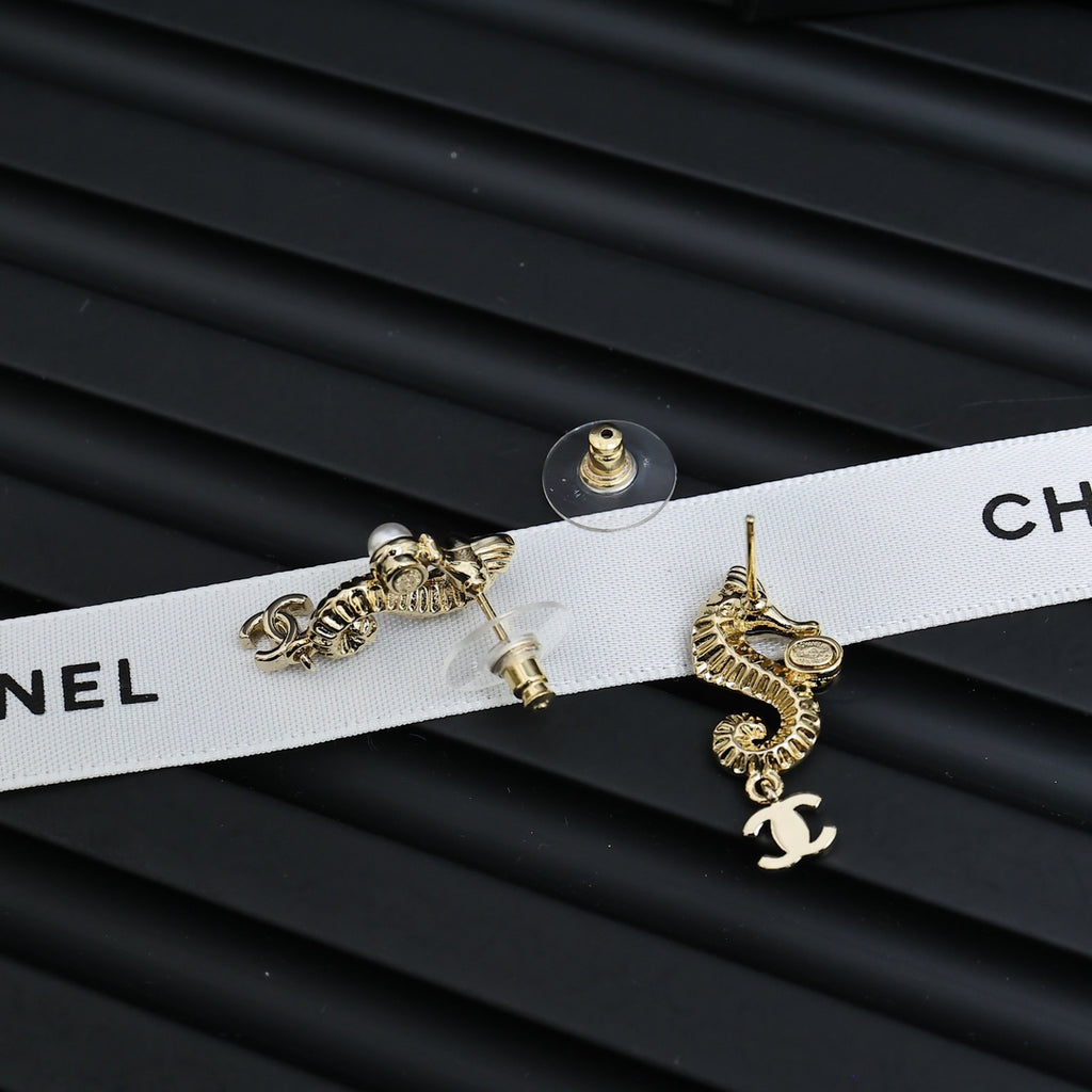 Gold-tone dangle earrings with pearl accents and Chanel CC charm, laid flat pair