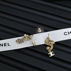 Gold-tone dangle earrings with pearl accents and Chanel CC charm, laid flat pair