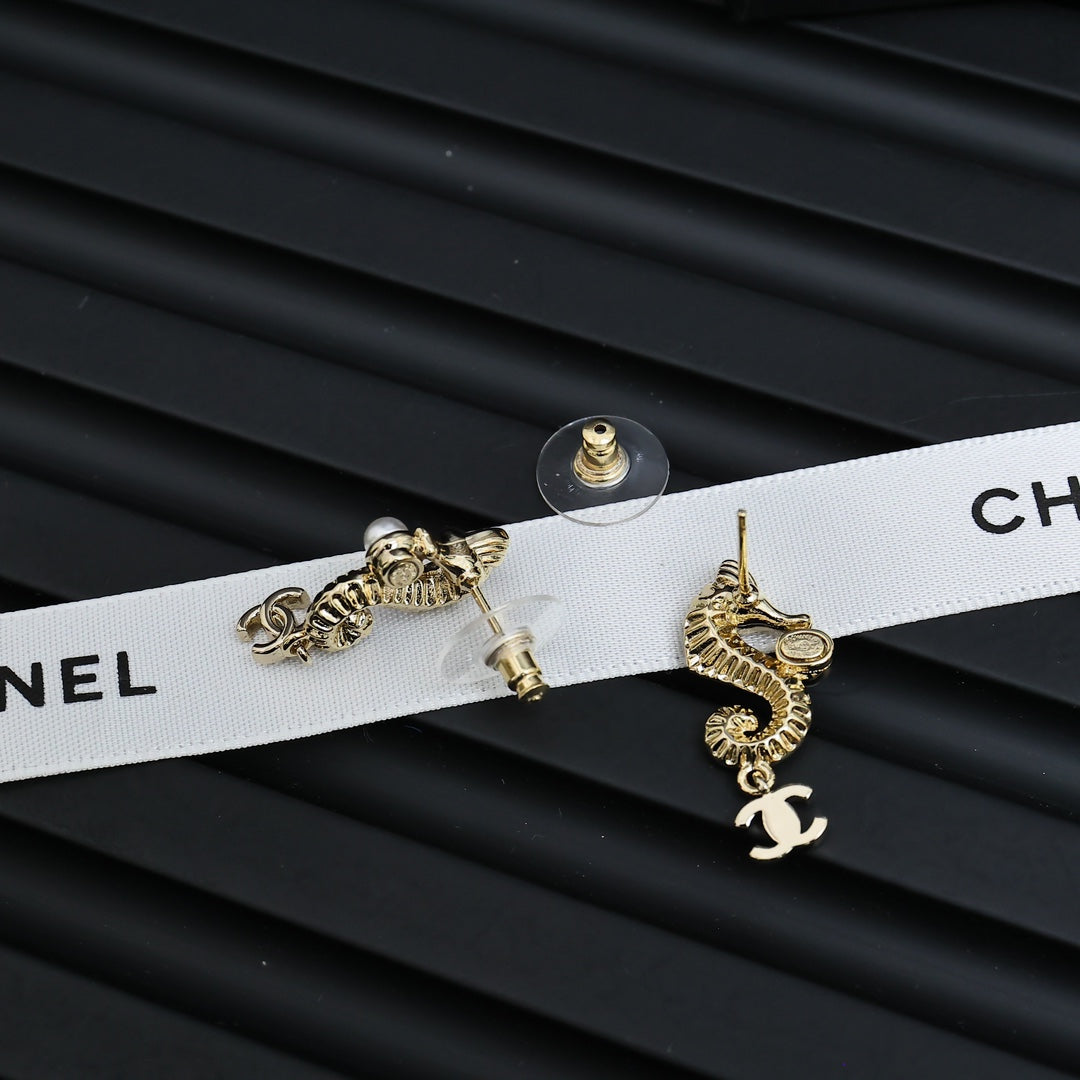 Gold-tone dangle earrings with pearl accents and Chanel CC charm, laid flat pair