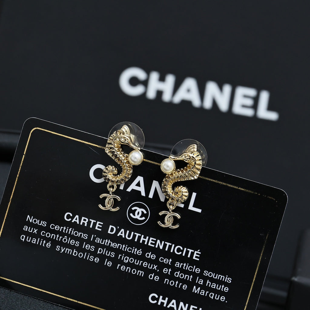 Gold-tone earrings with pearl accents and Chanel CC charm, close-up pair