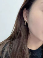 Gold-tone Chanel CC dangle earrings with pearl accents, worn on ear side view