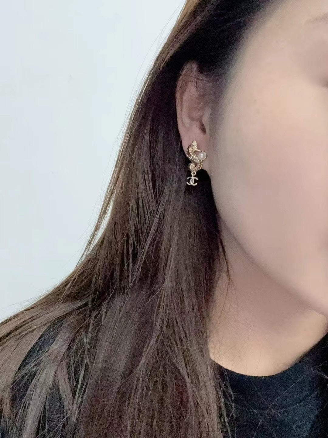 Gold-tone Chanel CC dangle earrings with pearl accents, worn on ear side view