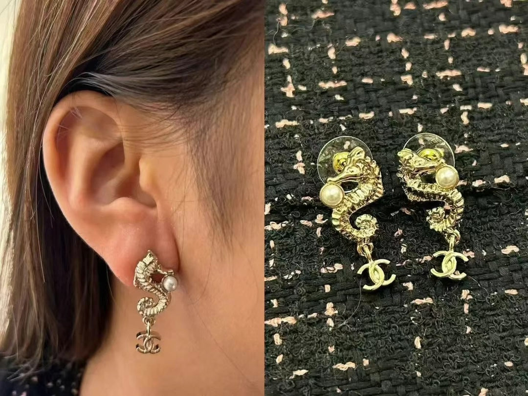 Chanel CC dangle earrings with pearl accents worn on ear, gold-tone pair
