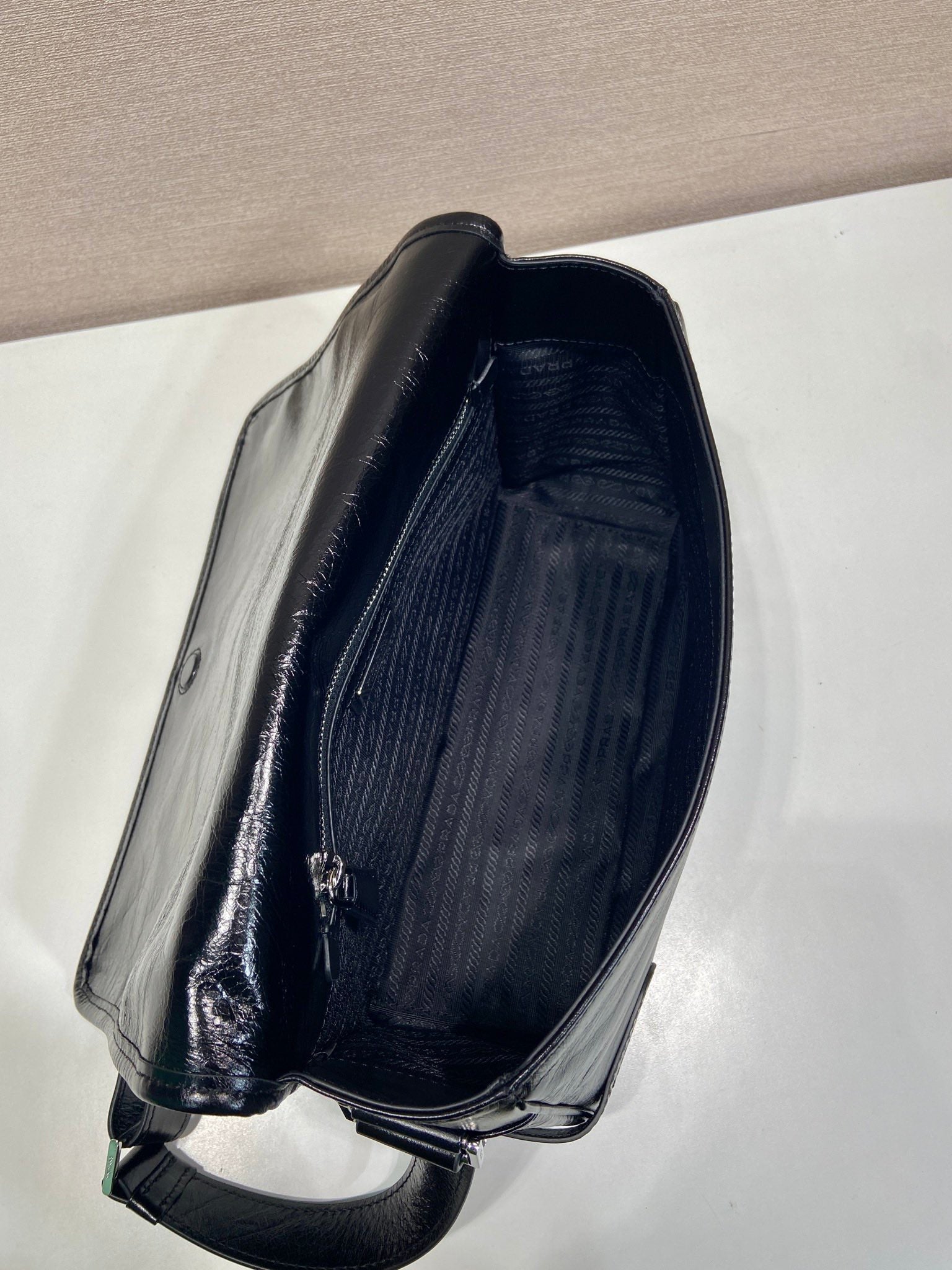 Dark leather bag with open top showing striped fabric interior and zipper pull